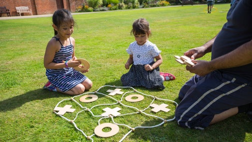 Visitors playing an outdoor game of noughts and crosses in the Cedar Garden at Tredegar House, Newport, Wales